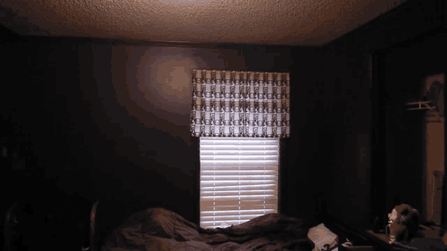 a dark bedroom with a bed and a window
