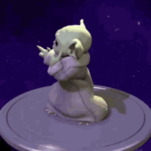 a 3d rendering of a baby yoda statue sitting on a purple surface .