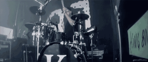 a man is playing drums in front of a wall that says king all