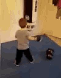 a young boy is standing in a room holding a glove .