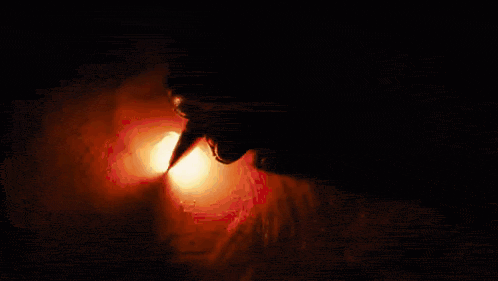 a close up of a person 's mouth with a flame coming out of it in the dark .