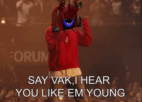 a man in a red hoodie is standing in front of a crowd and says " say vak i hear you like em young "