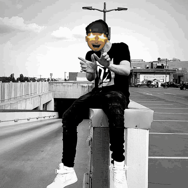 a man wearing a black shirt with the number 72 on it sits on a ledge in a parking lot