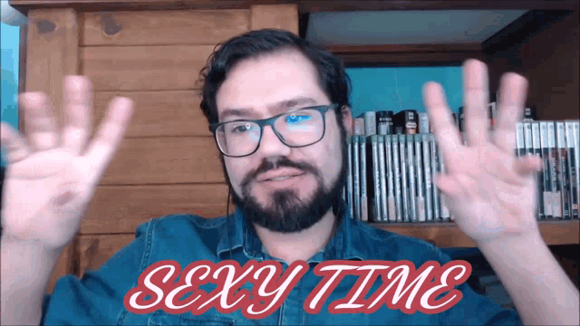 a man with glasses and a beard says sexy time with his hands up