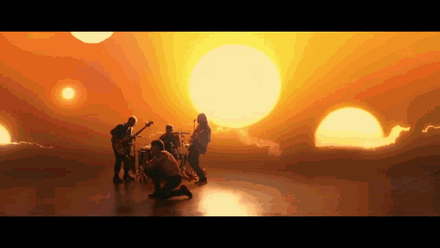 a group of people are playing music in front of a sunset