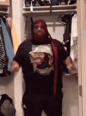 a man is standing in a closet wearing a t-shirt with a picture of a man on it .
