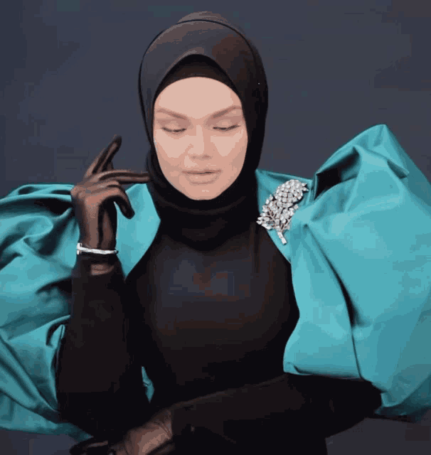 a woman wearing a black hijab and a teal jacket