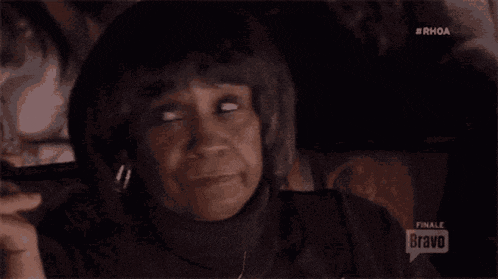 a woman sitting in a car with a bravo logo on the bottom