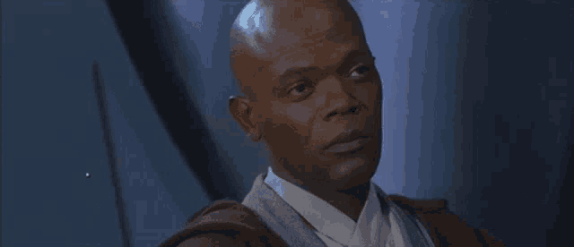 a bald man is wearing a brown robe and a white shirt