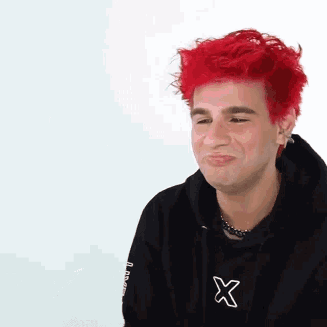 a young man with red hair is wearing a black hoodie with a white x on the sleeve .
