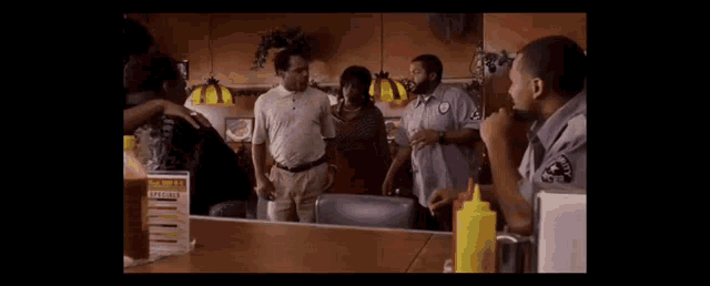 a group of people are standing around a table in a restaurant with a security guard .