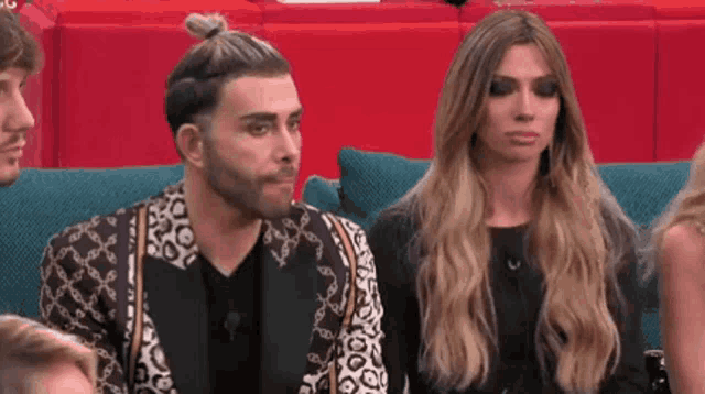 a man and a woman are sitting on a couch looking at something .