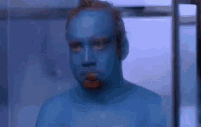 a man with blue paint on his face is standing in a room .