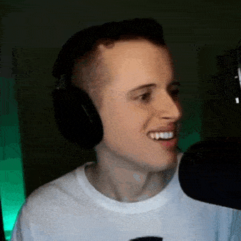 the man is wearing headphones and smiling in front of a microphone .
