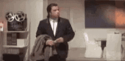 a man in a suit and tie is standing in a room holding his jacket .
