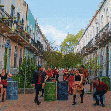 a group of people are walking down a street with barrels