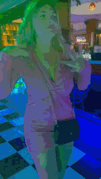 a woman in a pink dress is standing in a checkered floored room .