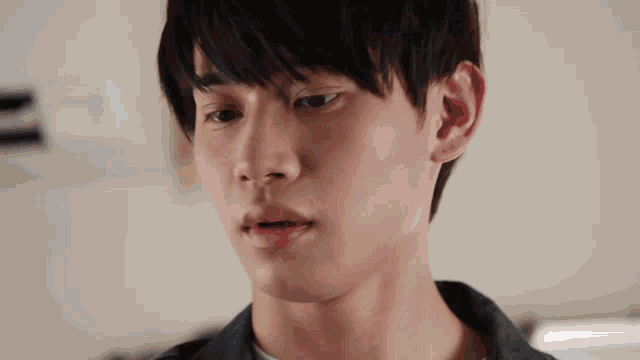 a close up of a young man 's face with a clock on the wall in the background .