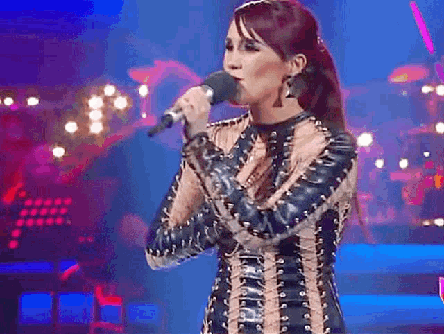 a woman singing into a microphone on stage