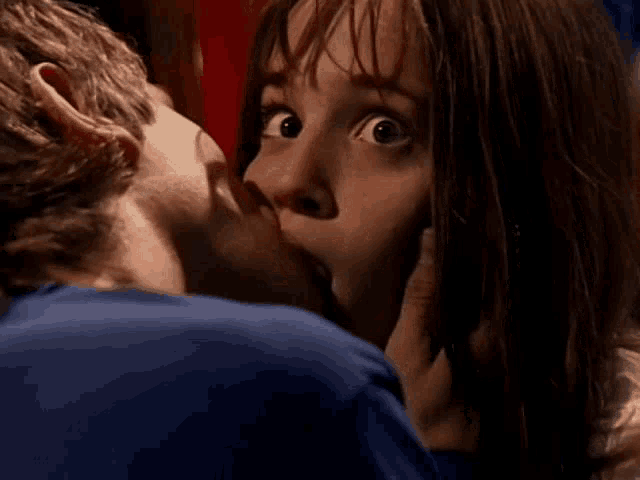 a man kissing a woman on the cheek with a surprised look on his face