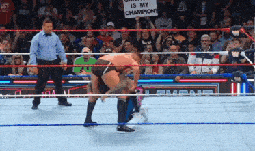 a man in a wrestling ring holds up a sign that says " gonna be is my champion "