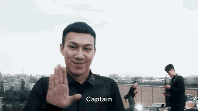 a man in a black shirt says captain in front of a city