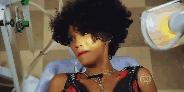 a woman with curly hair is sitting in an operating room with an o on her arm