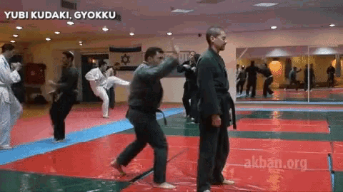 a group of men are practicing martial arts in a gym with yubi kudaki gyökku written above them