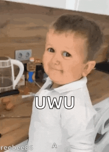 a baby is making a funny face while standing in a kitchen and smiling .
