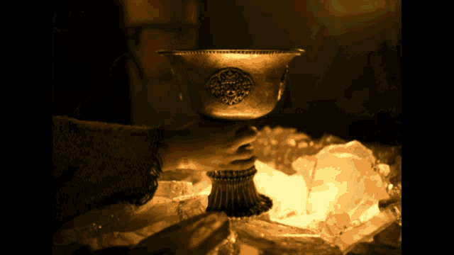 a person is holding a small gold cup with a circular design on it