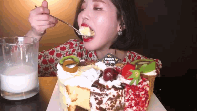 a woman is eating a birthday cake with a happy birthday sign on it