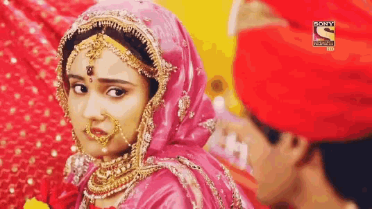 a woman in a pink dress is standing next to a man in a red turban with a sony logo in the corner