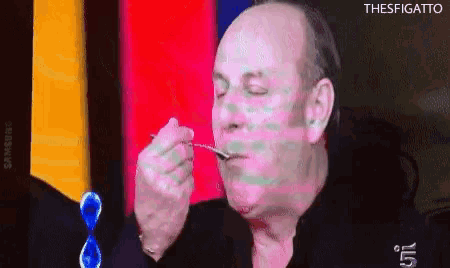 a bald man is eating something with a spoon and the word thesfigato is on the bottom