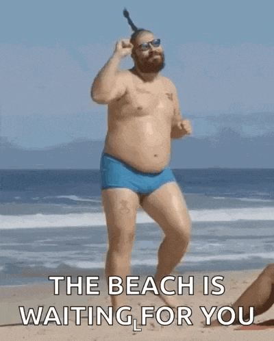 a shirtless man in blue swim trunks is standing on a beach with a toothbrush in his hair .