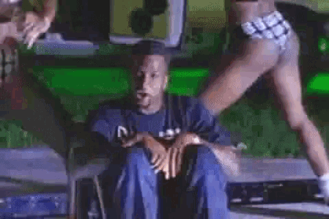 a man in a blue shirt is sitting in front of a woman in white shorts .