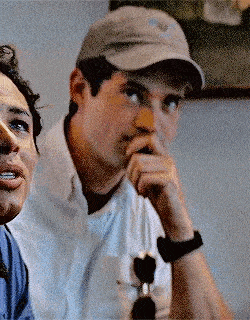 a man wearing a baseball cap is sitting next to another man .