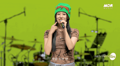 a woman singing into a microphone with the words fifty fifty live on the bottom right