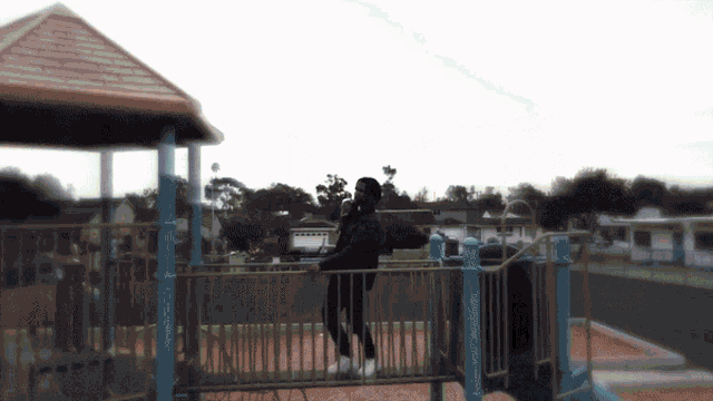 a woman sits on a swing at a playground with a gazebo in the background