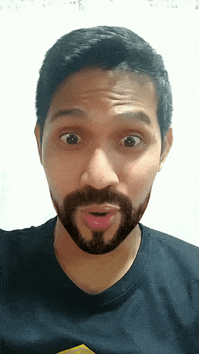 a man with a beard and a black shirt is making a funny face