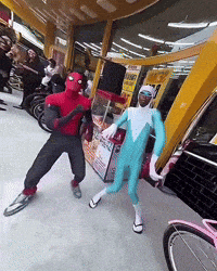 a man in a spiderman costume is dancing with another man in a blue suit