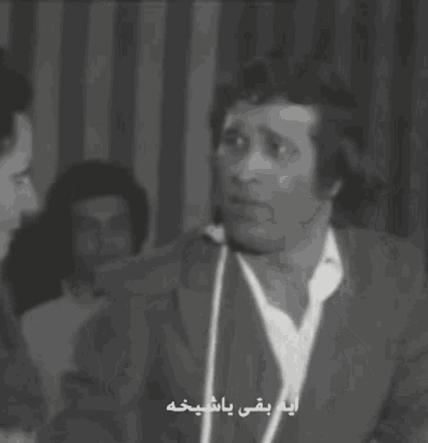 a black and white photo of a man and a woman with arabic writing on the bottom