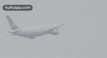 a plane is flying through a cloudy sky in a black and white photo .