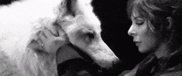 a black and white photo of a woman holding a white dog