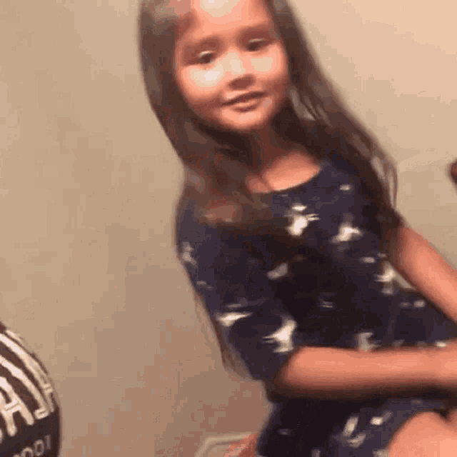 a little girl in a blue dress is sitting on a couch .