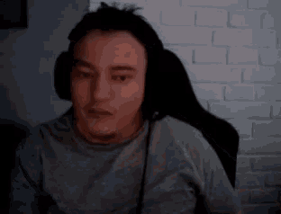 a man wearing headphones is sitting in front of a white brick wall