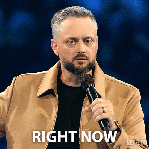 a man holding a microphone in front of a blue background that says right now