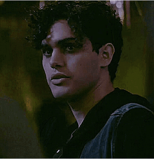 a young man with curly hair is looking at the camera .
