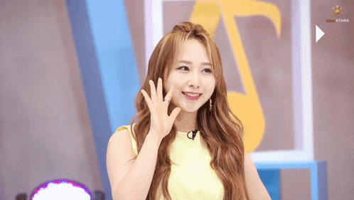a woman in a yellow top is waving her hand in front of a play button