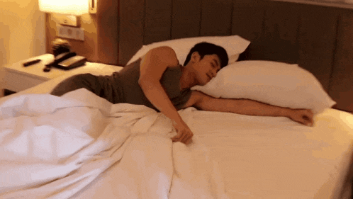a man is sleeping in a bed with white sheets