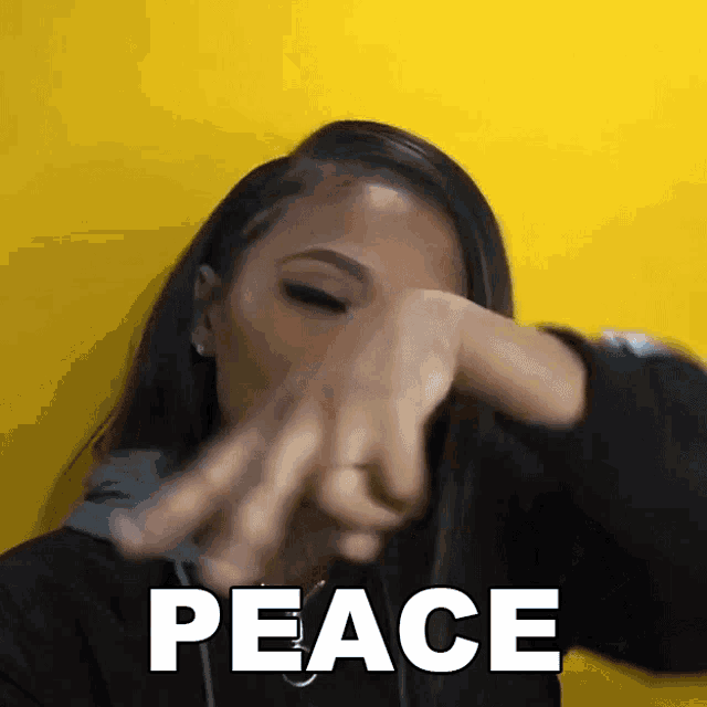 a woman covering her face with her hands in front of a yellow background with the word peace written on it